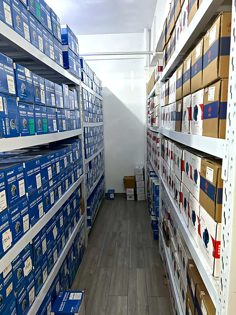 Shelving aisle in the Chengdu warehouse, JHAEM cartons on the left rack and mixed brand cartons on the right.