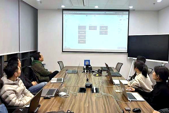 Fuzhihui staff at laptops in the Chengdu office meeting room, facing a projected screen.